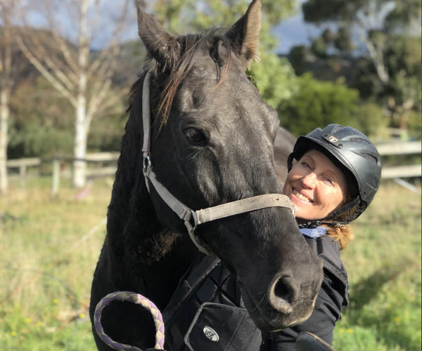 Annette Kaitinis posing with her black horse Matty in Tasmania